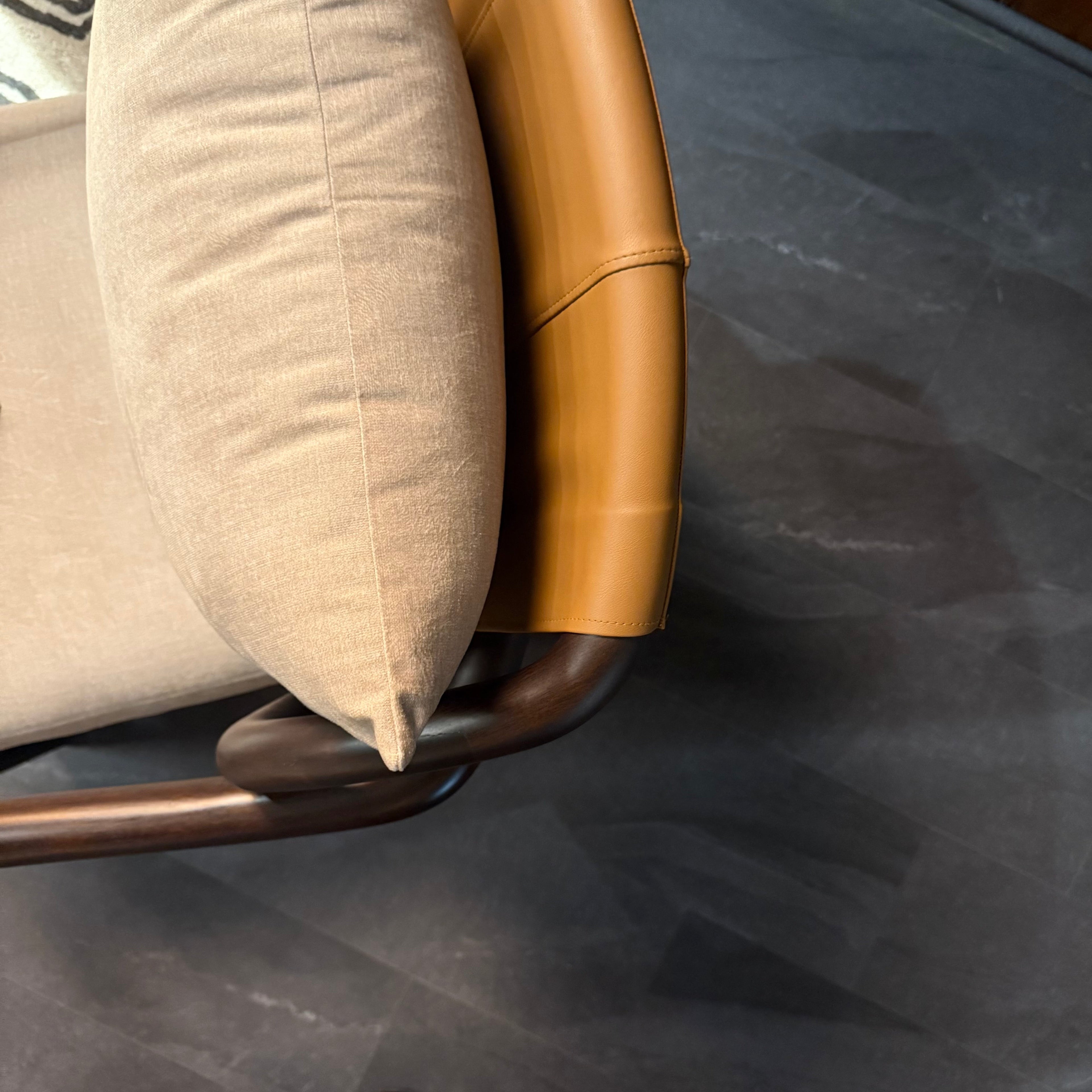 Close-up of a chair with beige cushion and gold metal frame on a dark surface.